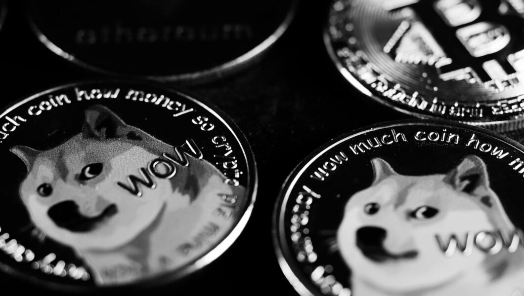 Monochrome image focusing on physical Dogecoin and Bitcoin coins, highlighting cryptocurrency.