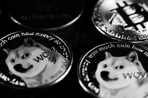 Monochrome image focusing on physical Dogecoin and Bitcoin coins, highlighting cryptocurrency.