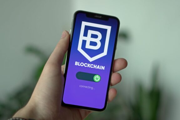 Close-up of a hand holding a smartphone with a blockchain app interface.